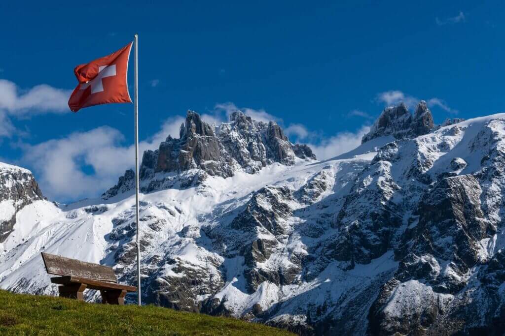 Die Schweizer Flagge weht vor schneebedeckten Bergen